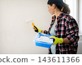 Woman Painter painting walls with a roller and White Paint During Painting Renovation Rooms 143611366