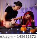 Mother With Little Daughter Preparing Room For Festive Halloween By Drawing A Pumpkin Face Together 143611372