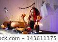 Cute Little Girl In A Halloween Witch Wig Plays With A Pumpkin And Prepares The Room For A Festive Party 143611375