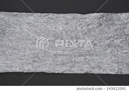 Crumpled translucent paper stripe on black background Crumpled translucent paper stripe on black background 143612091