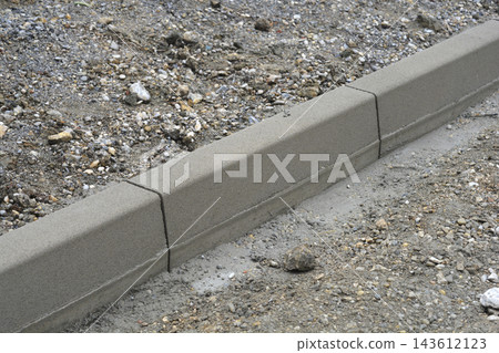 Concrete kerb stone installation on a construction site Concrete kerb stone installation on a construction site 143612123