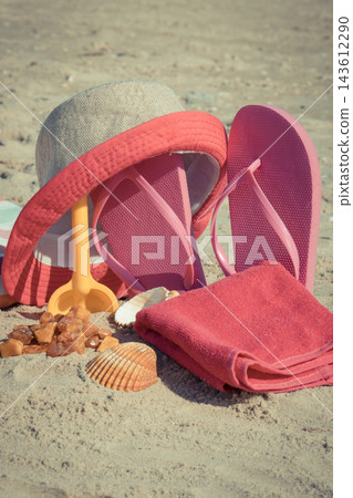 Different accessories for relax on sand at beach. Straw hat, slippes, towel. Summer time Different accessories for relax on sand at beach. Straw hat, slippes, towel. Summer time 143612290