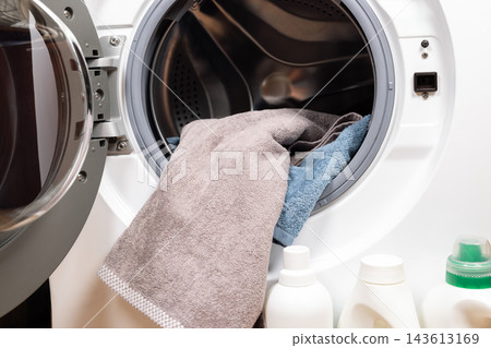 Loading laundry into washing machine with detergent 143613169