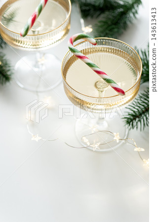 Festive glasses of champagne garnished with candy canes for winter holiday celebrations Festive glasses of champagne garnished with candy canes for winter holiday celebrations 143613413