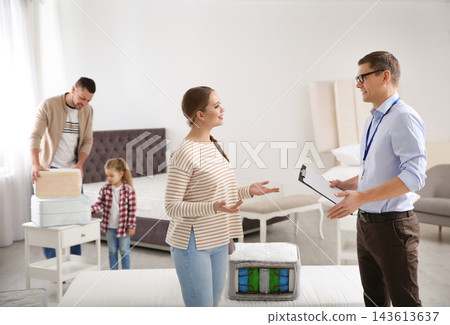 Salesman consulting young woman in mattress store Salesman consulting young woman in mattress store 143613637