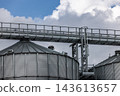 Metal grain silo structure for agricultural storage. Industrial steel construction used for storing grain and crops, photographed outdoors with a focus on farming, industry and rural infrastructure. 143613657