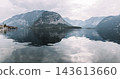 Panoramic view of Lake Hallstatt (Hallstatter See) in Austria, surrounded by majestic Alpine mountains with reflections on calm water and the historic village of Hallstatt on the shore. 143613660