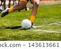 Soccer player in yellow uniform playing football on a green grass field, close-up action shot focused on the ball and legs during a match or training. 143613661