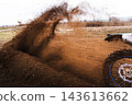 Motocross bike kicking up dirt on an off-road track, close-up of rear wheel with flying soil and dust during a race. 143613662