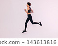 Full length of a young slim woman in black fitness wear running in a studio 143613816