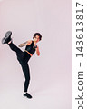 Slim woman in black sportswear practicing a leg kick 143613817