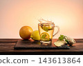 Glass cup with lemon, mint, and crown splash on a slate coaster. Ginger and mint in foreground, orange and lemon in background against soft pink backdrop. 143613864