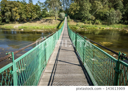 Suspension footbridge over the river Suspension footbridge over the river 143613909