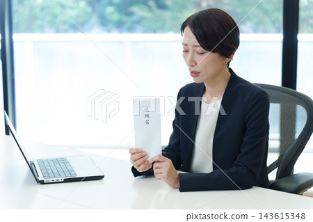 一位神情憂慮的女商人手持辭職信。 一位神情憂慮的女商人手持辭職信。 143615348