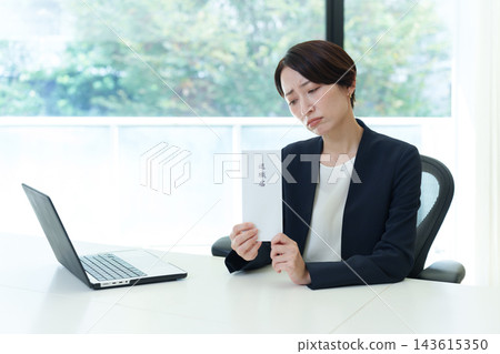 一位神情憂慮的女商人手持辭職信。 143615350