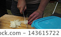Woman Slicing White Onion on Wooden Cutting Board 143615722