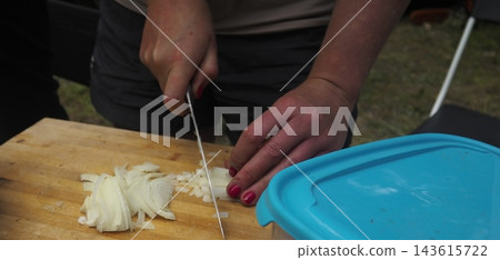 Woman Slicing White Onion on Wooden Cutting Board 143615722