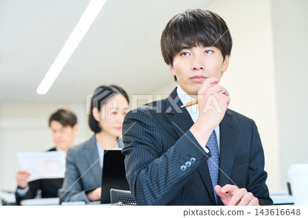 一位年輕的辦公室職員正在辦公室與團隊成員一起查看文件。 一位年輕的辦公室職員正在辦公室與團隊成員一起查看文件。 143616648