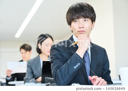 一位年輕的辦公室職員正在辦公室與團隊成員一起查看文件。 一位年輕的辦公室職員正在辦公室與團隊成員一起查看文件。 143616649