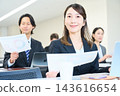 一位年輕的辦公室職員正在辦公室與團隊成員一起查看文件。 143616654