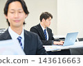 一位年輕的辦公室職員正在辦公室與團隊成員一起查看文件。 143616663