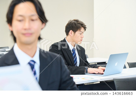 一位年輕的辦公室職員正在辦公室與團隊成員一起查看文件。 一位年輕的辦公室職員正在辦公室與團隊成員一起查看文件。 143616663