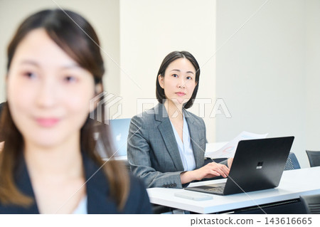 一位年輕的辦公室職員正在辦公室與團隊成員一起查看文件。 一位年輕的辦公室職員正在辦公室與團隊成員一起查看文件。 143616665
