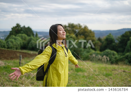 A female hiker takes a deep breath in a hilly area. A female hiker takes a deep breath in a hilly area. 143616784