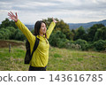 A side shot of a female hiker relaxing in a hilly area. 143616785