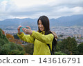 A woman takes a selfie with the mountains visible from the Shibusawa Hills in the background. 143616791