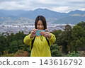 A woman takes a selfie with the mountains visible from the Shibusawa Hills in the background. 143616792