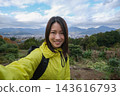 A woman takes a selfie with the mountains visible from the Shibusawa Hills in the background. 143616793