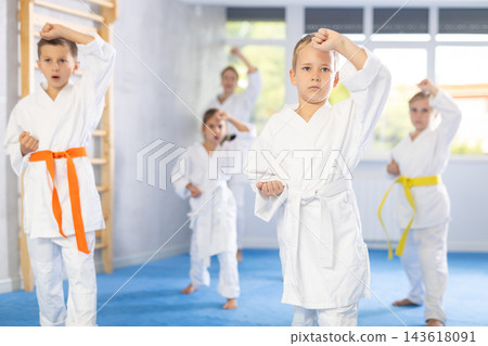 Children students repeat position and perform sequence of punches and painful techniques kata Children students repeat position and perform sequence of punches and painful techniques kata 143618091