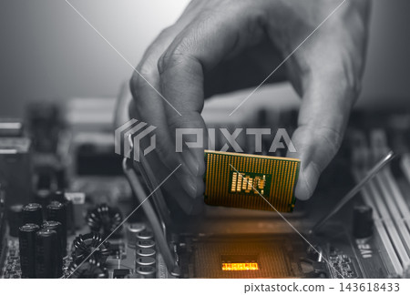 Technician holding CPU processor above motherboard socket during computer hardware repair, selective color highlights semiconductor chip for system upgrade, maintenance and electronic engineering Technician holding CPU processor above motherboard socket during computer hardware repair, selective color highlights semiconductor chip for system upgrade, maintenance and electronic engineering 143618433