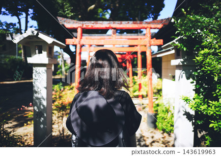 一位女子背對著朱紅色鳥居祈禱。 143619963