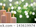 Lit candles with festive holiday green bokeh lights in background 143619974