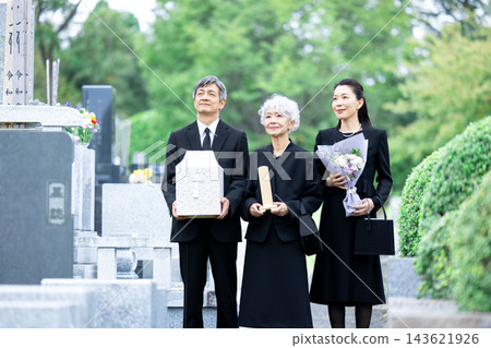 骨灰安葬:一家人在墓園安葬骨灰。 骨灰安葬:一家人在墓園安葬骨灰。 143621926