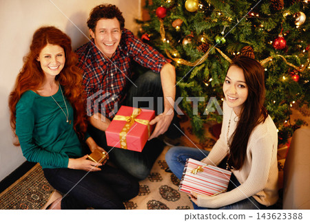 Friends, Christmas and portrait with present, tree with decor in living room in winter holiday. Gift giving, smile or people sitting on floor together, Christian celebration on Xmas eve or happiness Friends, Christmas and portrait with present, tree with decor in living room in winter holiday. Gift giving, smile or people sitting on floor together, Christian celebration on Xmas eve or happiness 143623388