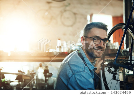 Portrait, smile and man with bicycle for mechanic career, business owner and working in maintenance garage. Mature male person, technician and bike inspection in cycling workshop for wheel repair Portrait, smile and man with bicycle for mechanic career, business owner and working in maintenance garage. Mature male person, technician and bike inspection in cycling workshop for wheel repair 143624499