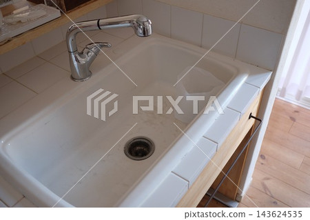 A garbage can placed in the kitchen sink A garbage can placed in the kitchen sink 143624535