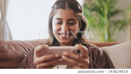 Couch, watch and girl with cellphone, smile and video in social media, online and digital and house. App, streaming and movie for woman, enjoy and happy in living room, relax and mobile with internet 143624919