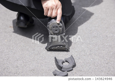 一名男子正在檢查鞋子破損的鞋跟。 一名男子正在檢查鞋子破損的鞋跟。 143624946