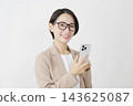 A middle-aged businesswoman using a smartphone; white background; looking directly at the camera. 143625087