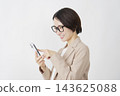 A middle-aged businesswoman using a smartphone; white background. 143625088