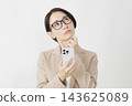 A middle-aged businesswoman thinking with her smartphone in hand, against a white background. 143625089