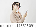 A middle-aged businesswoman, holding a smartphone, imagines herself against a white background. 143625091