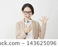 A middle-aged businesswoman smiles in surprise while holding her smartphone against a white background. 143625096