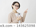 A middle-aged businesswoman holding a smartphone and pointing to the right; white background. 143625098