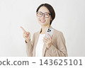 A middle-aged businesswoman holding a smartphone and pointing to the left; white background. 143625101