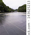 Wide Japanese cobblestone streets wet with rain, and people holding umbrellas. 143625213